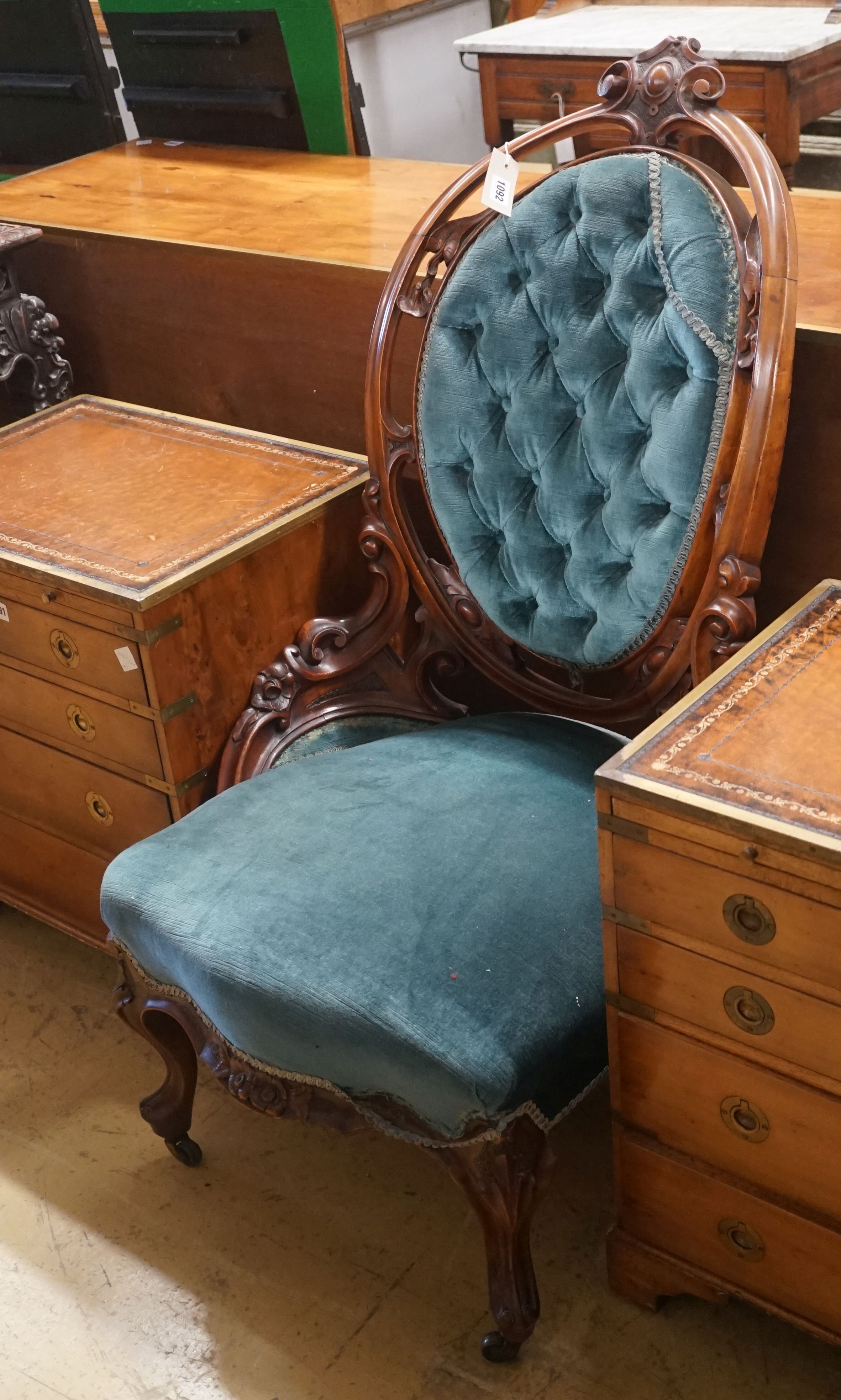 A Victorian carved mahogany spoon back salon chair with buttoned blue upholstery